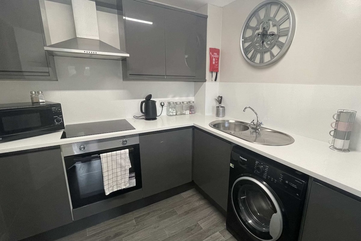 A modern kitchen with a microwave, oven, sink, and washing machine.