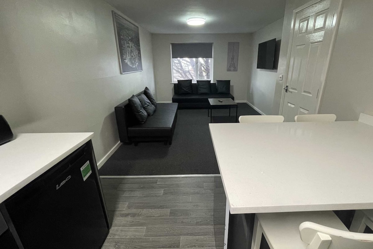 A compact room with a white table, a black sofa, and a small black cabinet.