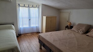 Une chambre à coucher avec un lit, une armoire, une table de chevet et une fenêtre avec des rideaux.