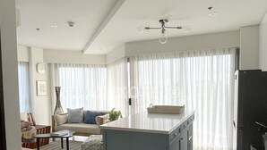 Una sala de estar moderna con sofá, mesa de centro y comedor con mostrador de cocina.