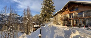 Eine Chalet mit Steinaußenwand, Holzbalkon und verschneiter Landschaft.