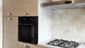 A kitchen with a built-in oven, a gas stove, and wooden cabinets. - LARGE APARTMENT 60 KM FROM ROME (Vignanello)
