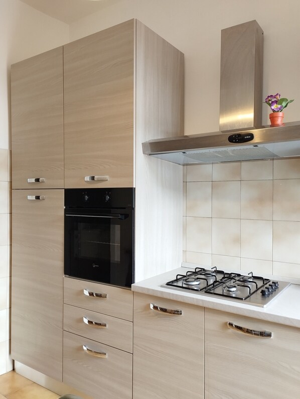 A kitchen with a built-in oven, a gas stove, and wooden cabinets.