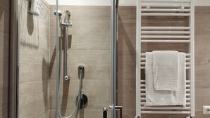 A shower with a glass door, a towel rack with a white towel, and a shower head. - LARGE APARTMENT 60 KM FROM ROME (Vignanello)
