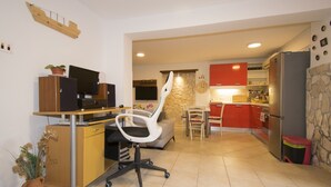 A compact kitchen with a dining area, a small office setup, and a stone accent wall. - Apartment Maja 2 (Premantura)