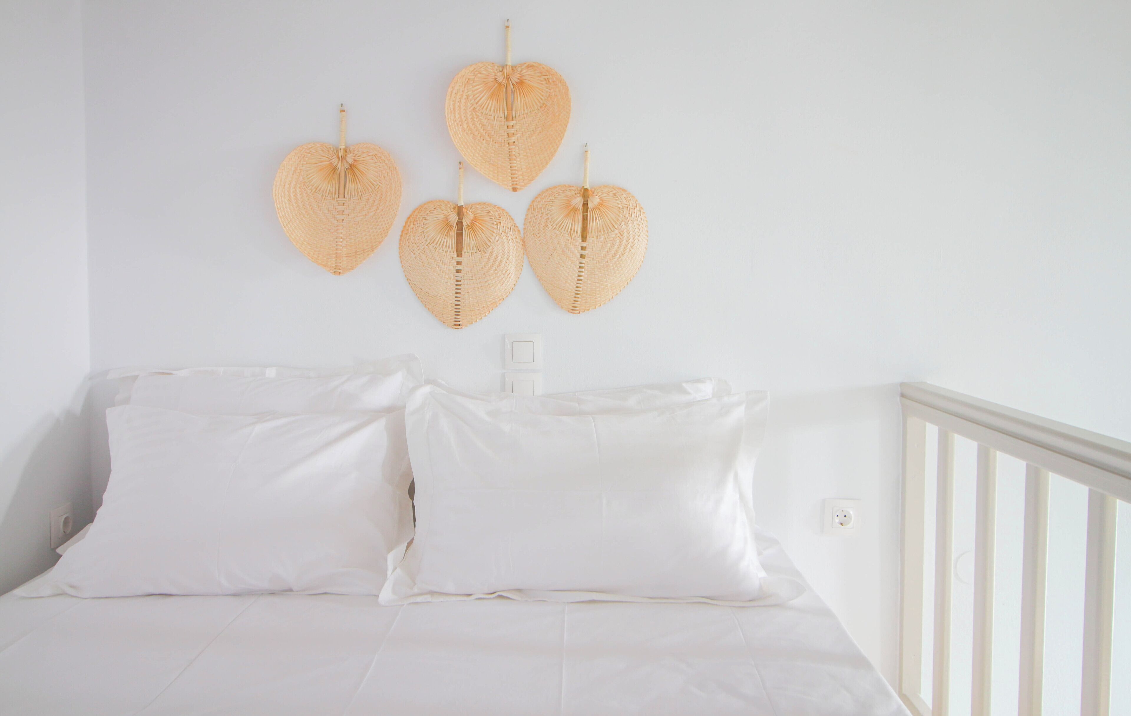 A white bedroom with a bed, white pillows, and a white railing.
