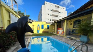 A swimming pool with a blue interior, surrounded by a tiled patio area. - Mananaue Villa (Ipojuca)