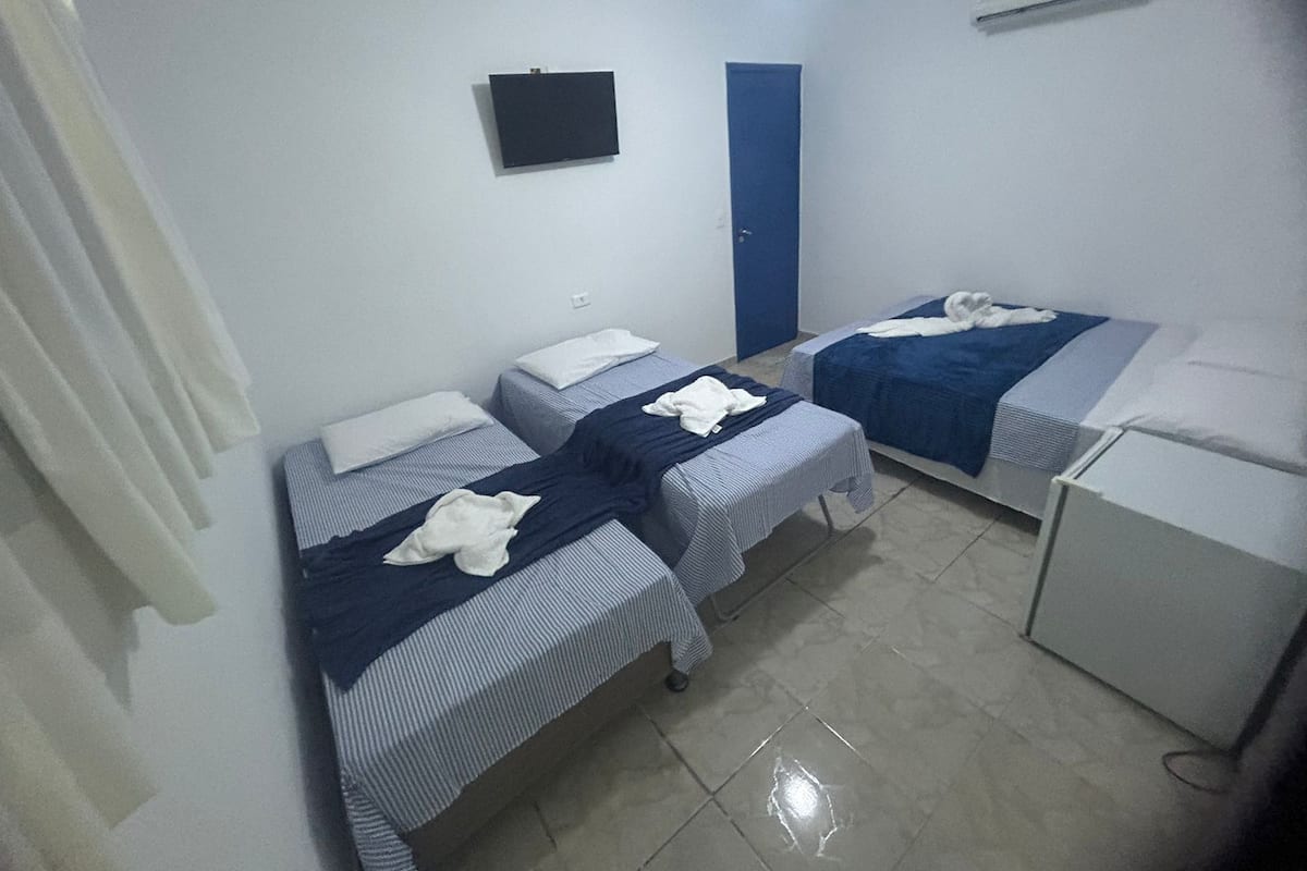 Una habitación pequeña y limpia con dos camas, un escritorio y una puerta azul.