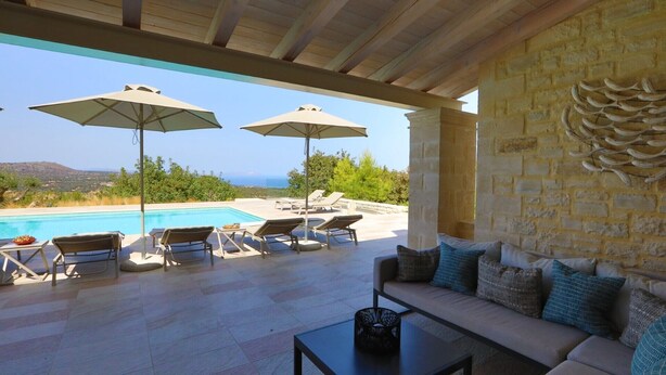A poolside area with lounge chairs, umbrellas, and a sofa. - Luxury villa with a fantastic view, the pool can be heated (Rethymnon)
