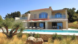 A two-story house with a swimming pool, outdoor seating, and a stone wall. - Luxury villa with a fantastic view, the pool can be heated (Rethymnon)