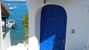 A blue door with a white wall and a stone staircase leading to a balcony overlooking a marina with boats. - Remarkable 3double-bed House in Daskalio (Lavreotiki)