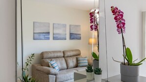 A modern living room with a sofa, cushions, a coffee table, and potted plants.