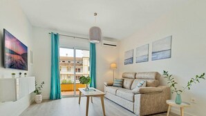 A modern living room with a sofa, a small table, and a view of a balcony.