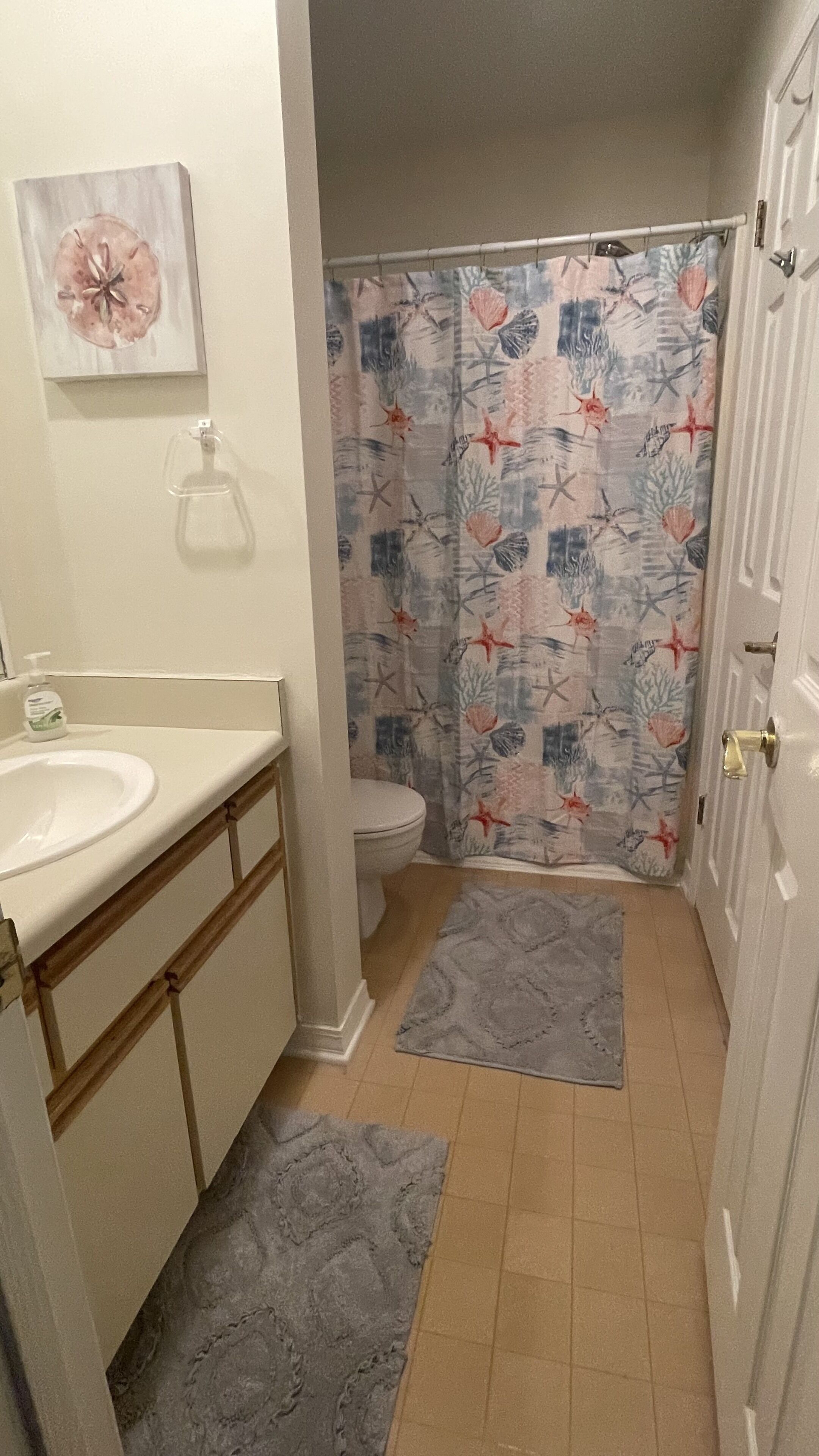 Une salle de bain avec des toilettes, un lavabo et un rideau de douche.