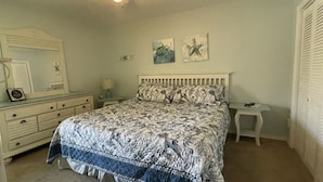 Une chambre à coucher comprenant un lit, une commode, une table de chevet et un miroir.