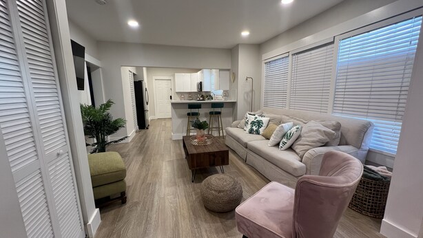 Una sala de estar moderna con un sofá, sillones, una mesa de centro y un comedor con una cocina al fondo.