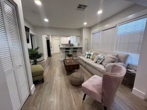 Una sala de estar moderna con un sofá, sillones, una mesa de centro y un comedor con una cocina al fondo.
