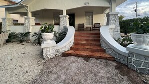 Una casa de dos pisos con fachada de piedra, un porche con dos sillas y el número 1274 en la pared frontal.