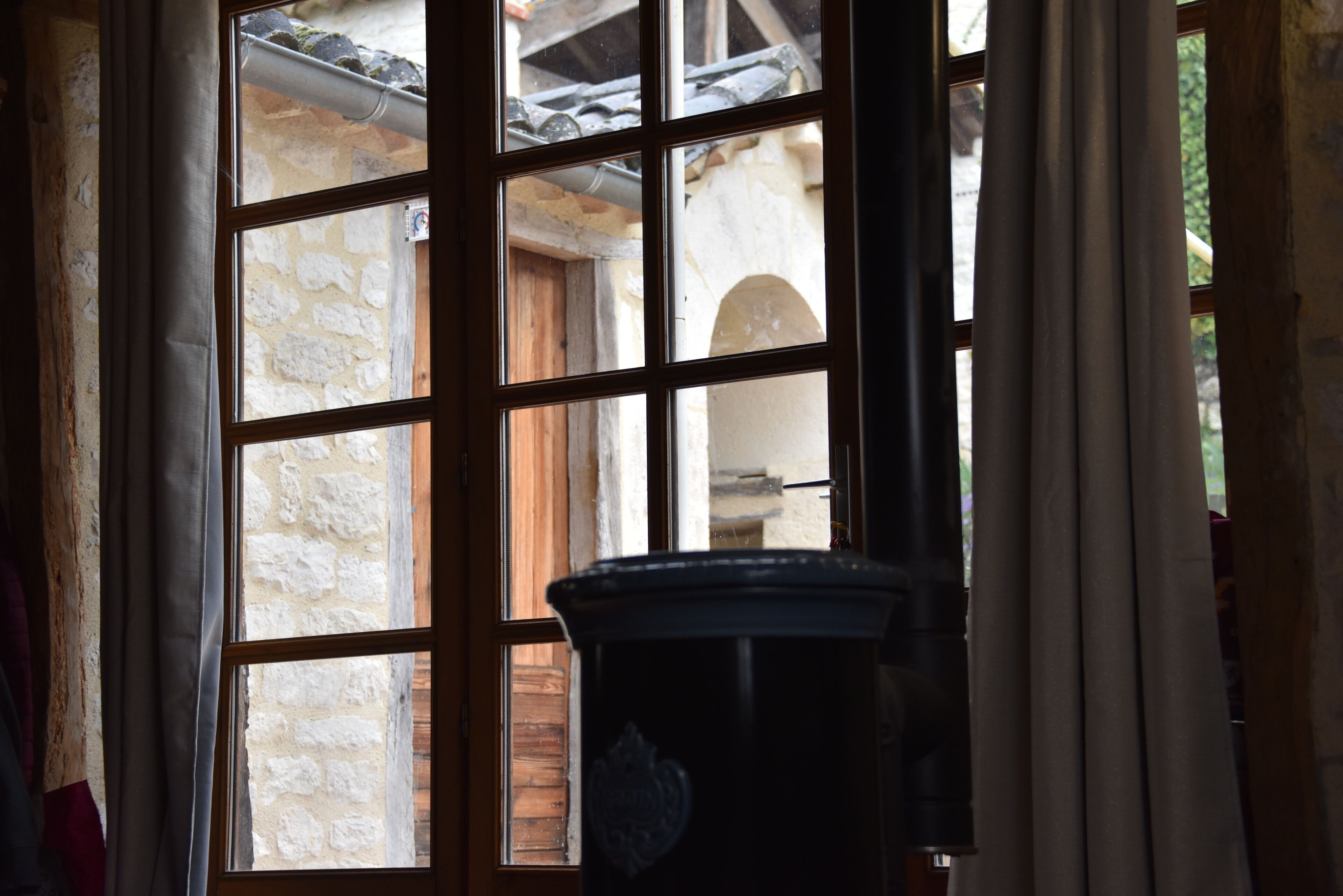 Una ventana con vista a un muro de piedra y una puerta de madera.