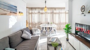 Ein modernes Wohnzimmer mit Sofa, Couchtisch, Fernseher und Essbereich.