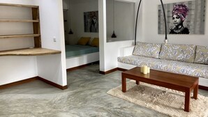 A living room with a sofa, a coffee table, a hanging lamp, and a painting on the wall.