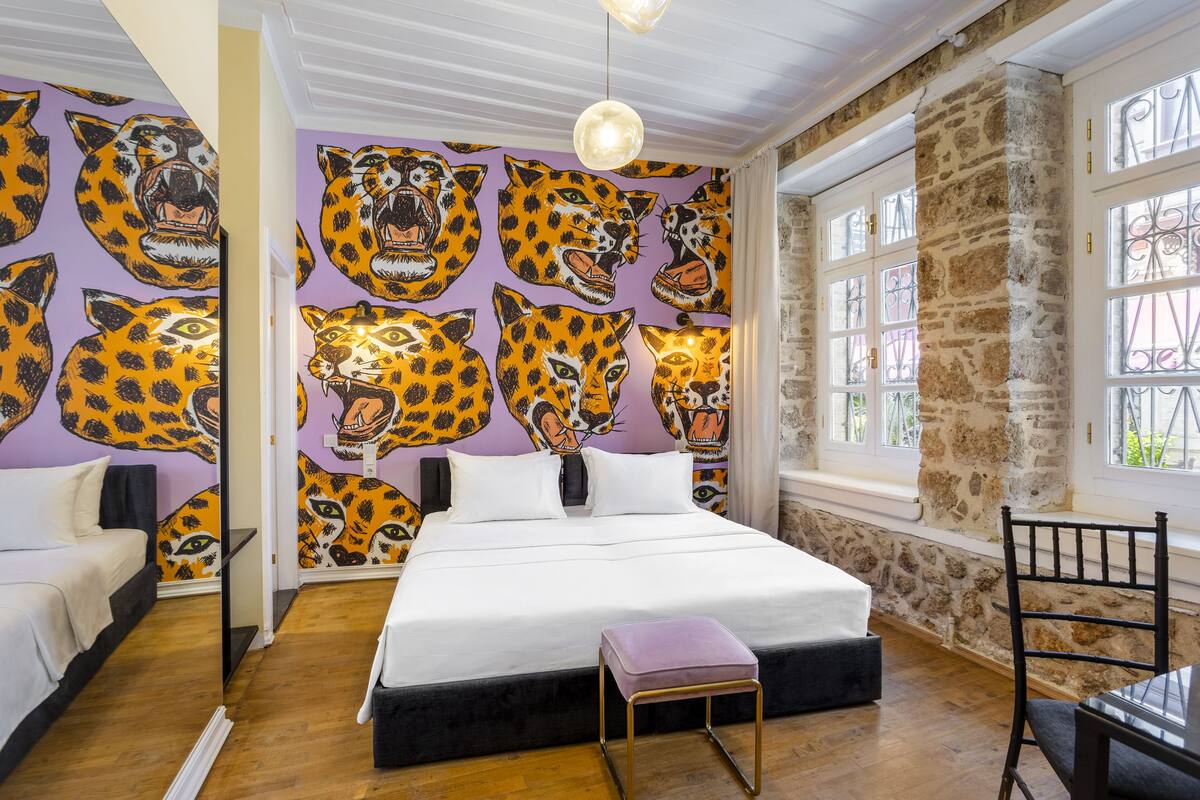Quarto com cama, cadeira, mesa e parede com estampas de leopardo.