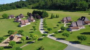 A residential area with houses, a playground, and a winding road. - Les SOURCES Premium, SPA, Swimming pool, Fishing pond, Playground, Games room... (Hautefort)