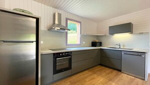 A modern kitchen with a stainless steel refrigerator, built-in oven, microwave, and dishwasher. - Les SOURCES Premium, SPA, Swimming pool, Fishing pond, Playground, Games room... (Hautefort)