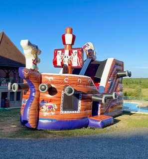 Een grote opblaasbare piratenschip met een stuurwiel en een piratenvlag met een doodskop en kruisbotten.