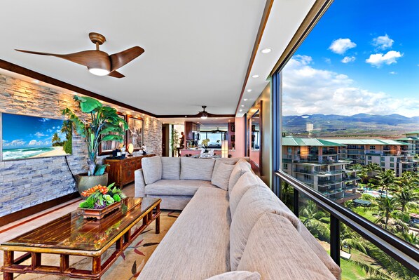 A modern living room with a large window offering a view of a resort and mountains.
