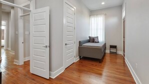 A bedroom with a bed, a nightstand, and a window with curtains. - Historical Charm with Modern Touch 5 Bedrooms 4 Bathrooms, Centrally Located (New Orleans)