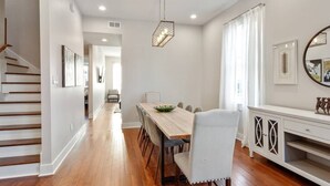 A dining area with a wooden table, chairs, and a white cabinet. - Historical Charm with Modern Touch 5 Bedrooms 4 Bathrooms, Centrally Located (New Orleans)