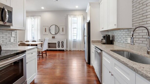 A modern kitchen with white cabinetry, a granite countertop, and a stainless steel sink. - Historical Charm with Modern Touch 5 Bedrooms 4 Bathrooms, Centrally Located (New Orleans)