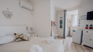 Een hotelkamer met een bed, nachtkastje, lamp, garderobe en raam.