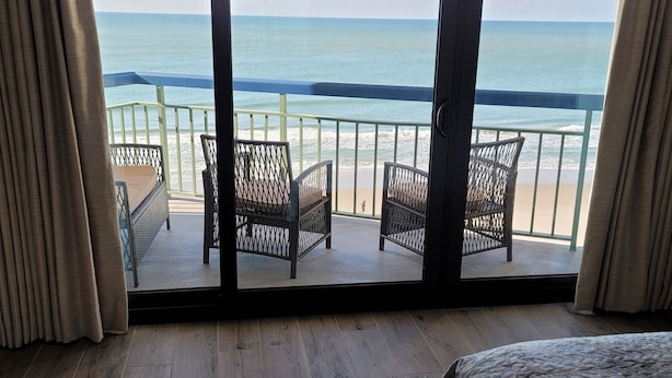 Un dormitori amb una gran porta corredissa de vidre que dona a un balcó amb vista a l'oceà.