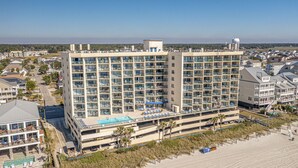 Un hotel gran amb múltiples pisos, una piscina al terrat i ubicació a primera línia de platja.