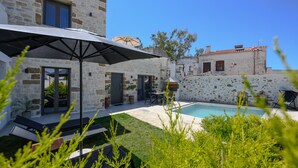 A stone building with a swimming pool, outdoor seating, and a large umbrella. - Stone project villa, pool,near tavern,supermarket (Pigi)