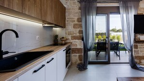 A kitchen with a wooden countertop, a black sink, and a stone wall. - Stone project villa, pool,near tavern,supermarket (Pigi)