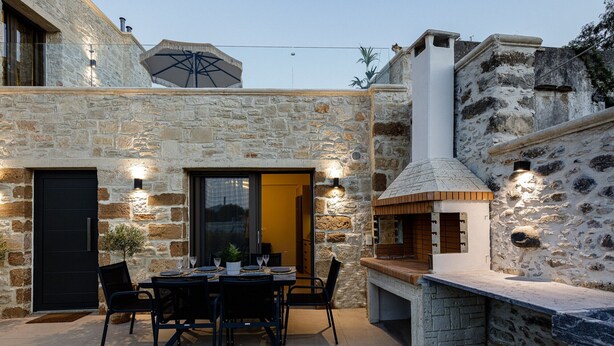 A stone exterior with a dining area, a black door, and a chimney. - Stone project villa, pool,near tavern,supermarket (Pigi)