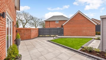 Enjoy a serene outdoor space with a well-manicured lawn and paved patio area.