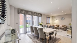 A modern living room with a dining area, a sofa set, and a large window with blinds. - Barfoot Close (Waterlooville)