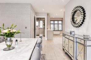 A modern kitchen with a marble countertop, a dining area with a gray sofa, and a kitchen island with a mirror.