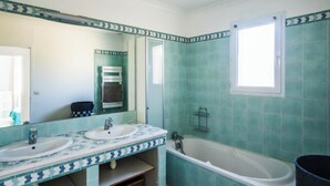 A bathroom with two sinks, a bathtub, and a window.