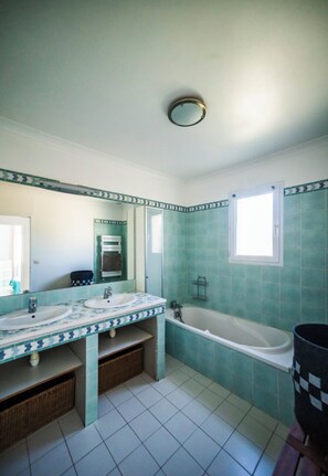 A bathroom with two sinks, a bathtub, and a window.