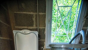 A compact laundry room with a washing machine and dryer, a window with a view of greenery, and a basket on the dryer.