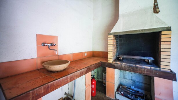 A kitchen with a wooden countertop, a bowl sink, and a brick oven.