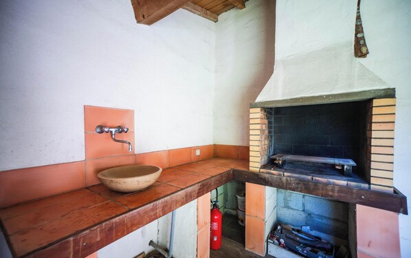 A kitchen with a wooden countertop, a bowl sink, and a brick oven.