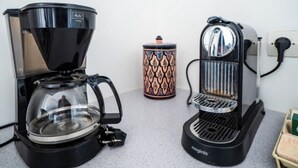 Two coffee makers on a countertop, a patterned mug, and a small box.