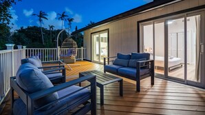 A modern outdoor deck with wooden flooring, a hanging chair, and two sofas.