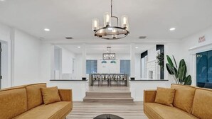 A modern living room with two sofas, a coffee table, and a chandelier.